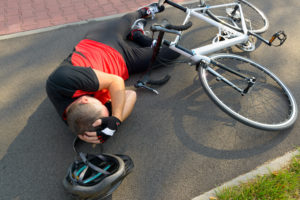 Picture of a Biker Clutching His Head on the Ground After a Bike Accident