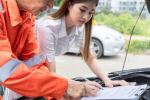 After car accident in San Jose, CA a woman signing the auto insurance claim document with a insurance representative.
