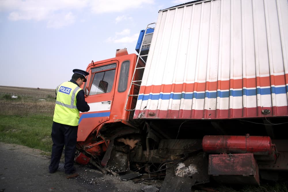 A truck collision on the road and a police officer observing the incident.