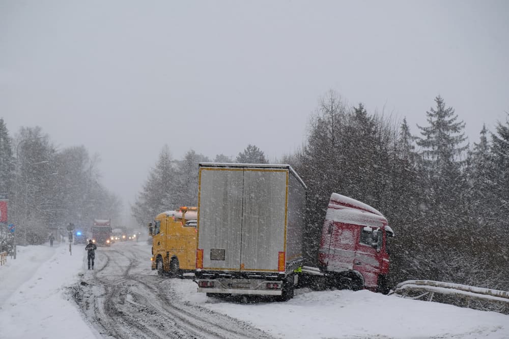 In severe winter conditions, a truck has been involved in a roadside accident, necessitating roadside assistance.