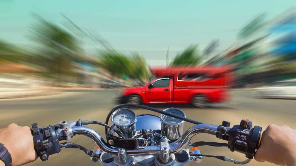 A man speeding on a motorcycle with the looming backdrop of an imminent accident.