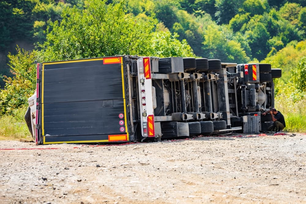During daylight hours, a substantial cargo truck has overturned in a road traffic incident.
