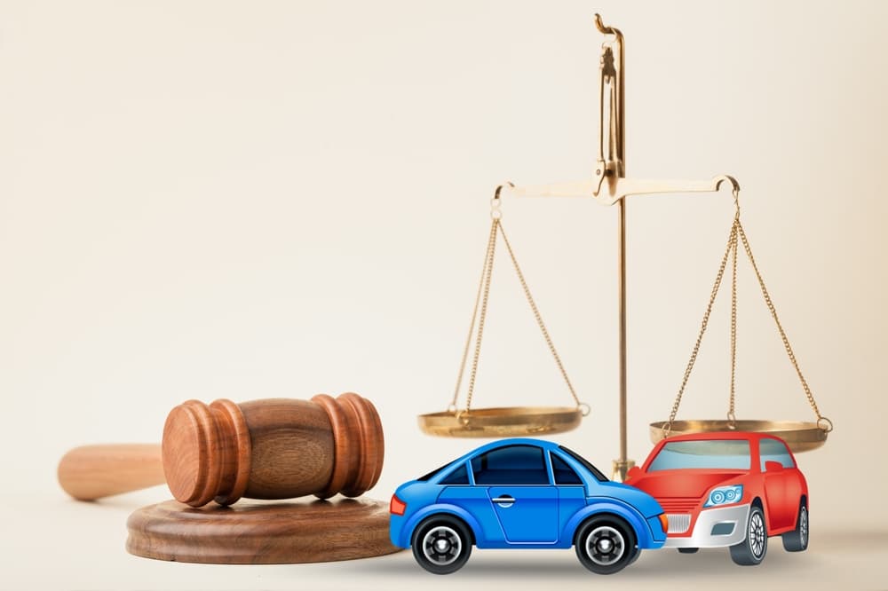 Miniature crashed autos adorn the courtroom table, accompanied by a gavel and two toy car models. Symbolizing legal services, civil trials, accident case studies, and insurance coverage.