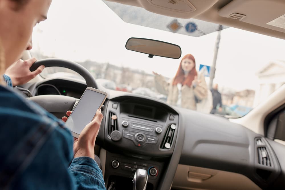 The car driver using mobile while driving and about to hitting a pedestrian on the road
